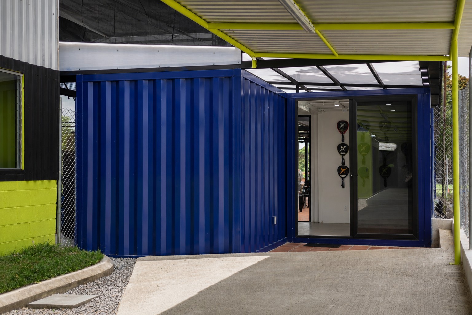 Padel Sport Center — acceso principal con contenedor azul